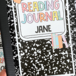 A black-and-white composition notebook with an editable label that reads "Reading Journal" in pastel-colored letters and "Jane" in bold black text. The label features cute clipart, including a small orange-and-white checkered notebook and blue heart-shaped accents. In the background, other labeled binders and notebooks are visible, featuring the same composition notebook theme.