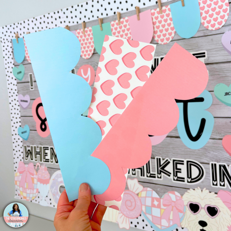 A close-up photo of three printable border designs in pastel pink, blue, and heart patterns, held by a teacher in front of the Swiftie-themed Valentine’s bulletin board. The borders match the soft, dreamy aesthetic of the set.