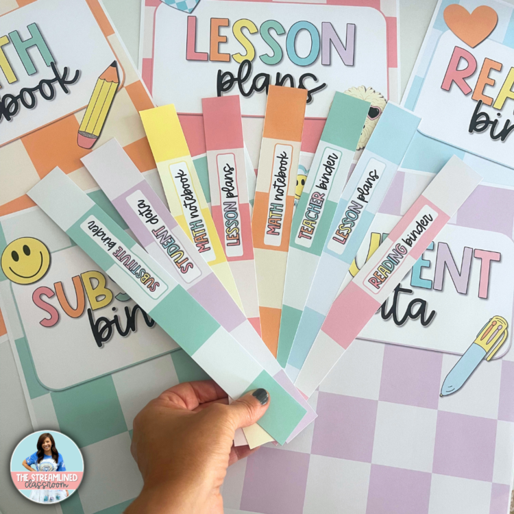 A hand holding a fan of pastel binder spines labeled for different uses, including lesson plans, student data, teacher binder, and math notebook. Matching covers are visible in the background.