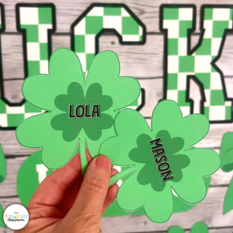 Close-up of a hand holding two editable clover name pieces labeled "Lola" and "Mason," printed in vibrant green with a darker green center.