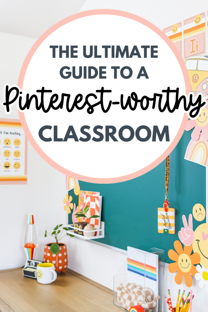 A bright and colorful classroom featuring a teal bulletin board decorated with smiley faces, rainbows, and retro-inspired decor. The desk area includes a lava lamp, a small potted plant, and rainbow-themed stationery. A large white circle overlay with bold text reads: "The Ultimate Guide to a Pinterest-Worthy Classroom," with a stylish mix of script and block fonts. The pin has a fun, inviting aesthetic perfect for teachers looking for classroom decor inspiration.