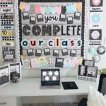 “You Complete Our Class” bulletin board display in pastel and black-and-white, surrounded by alphabet cards, shapes, and number posters with trendy 90s-style decor.